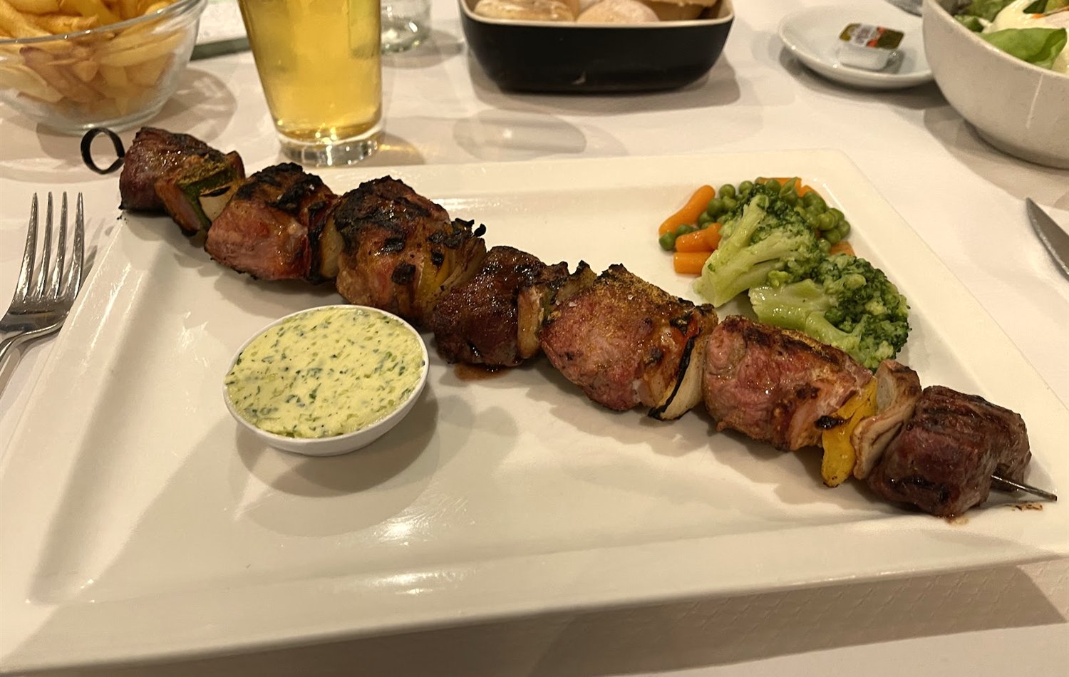 Grilled meat skewer with fries and beer
